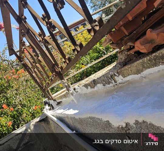 איטום גג עם חומר לבן ליד מעקה ברזל